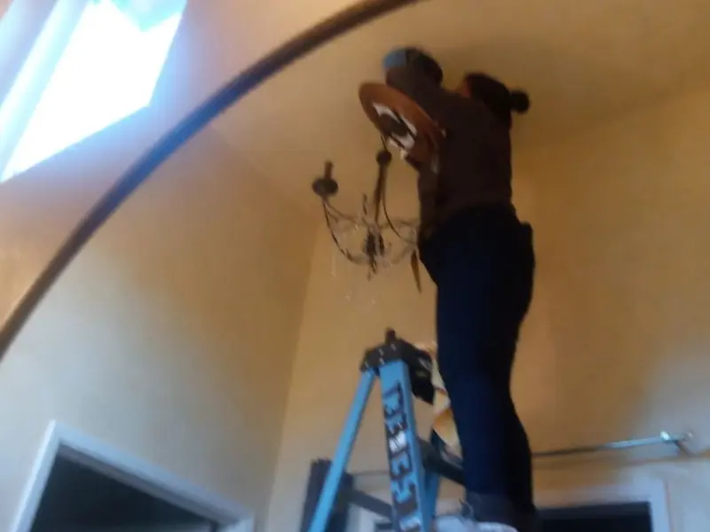 Electrician installing a chandelier in a Mount Airy residence